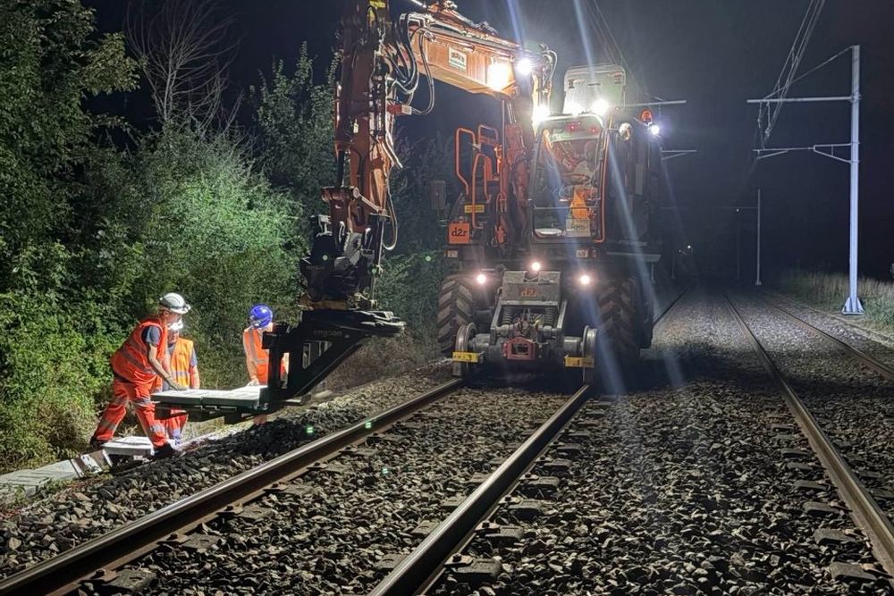 Intervention de nuit sur voie ferrée avec un engin rail-route, opérateurs en tenue haute visibilité